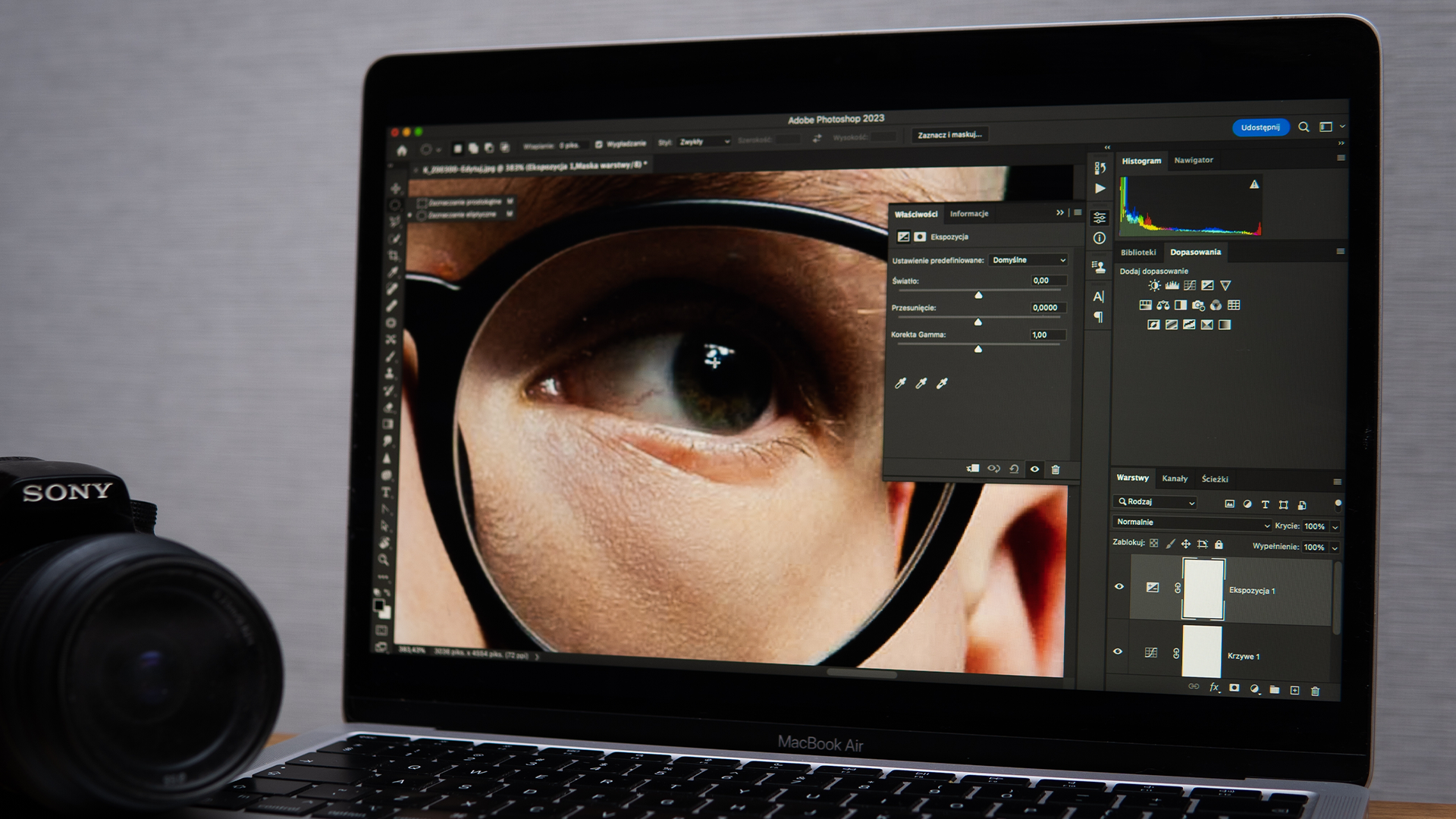 Adobe Photoshop öppet på en datorskärm med ett fotoredigeringsprojekt, tillsammans med en Sony-kamera