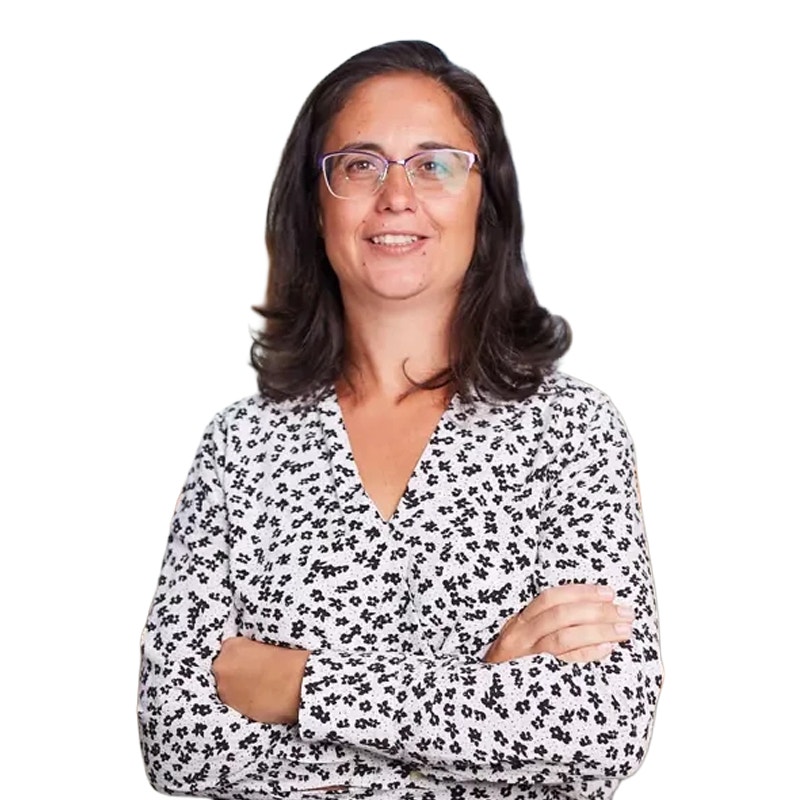 Porträttfoto av en kvinna med långt svart hår och glasögon, klädd i en vit blus med svart mönster.