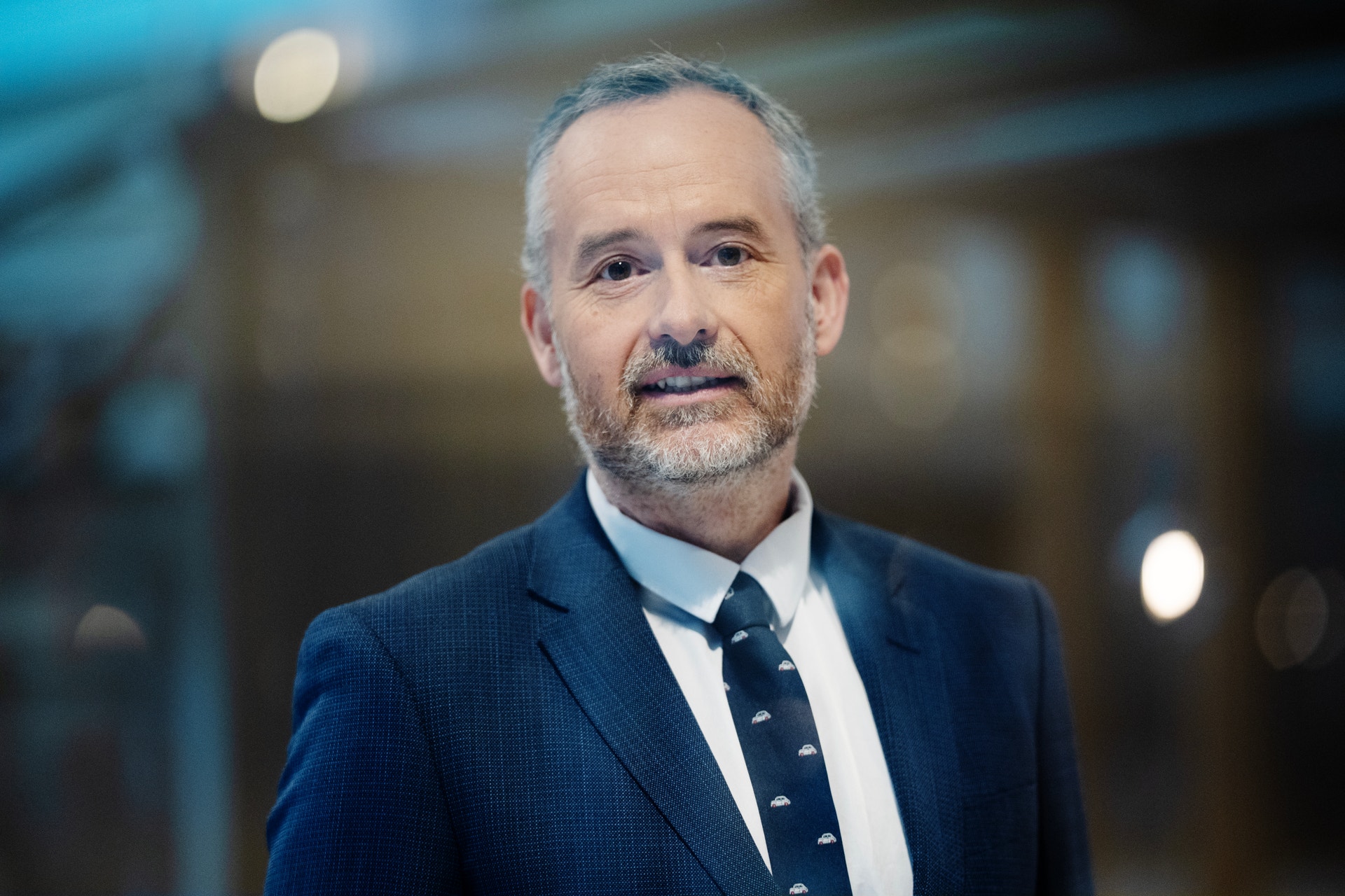 Porträtt av en man i mörkblå kostym och slips