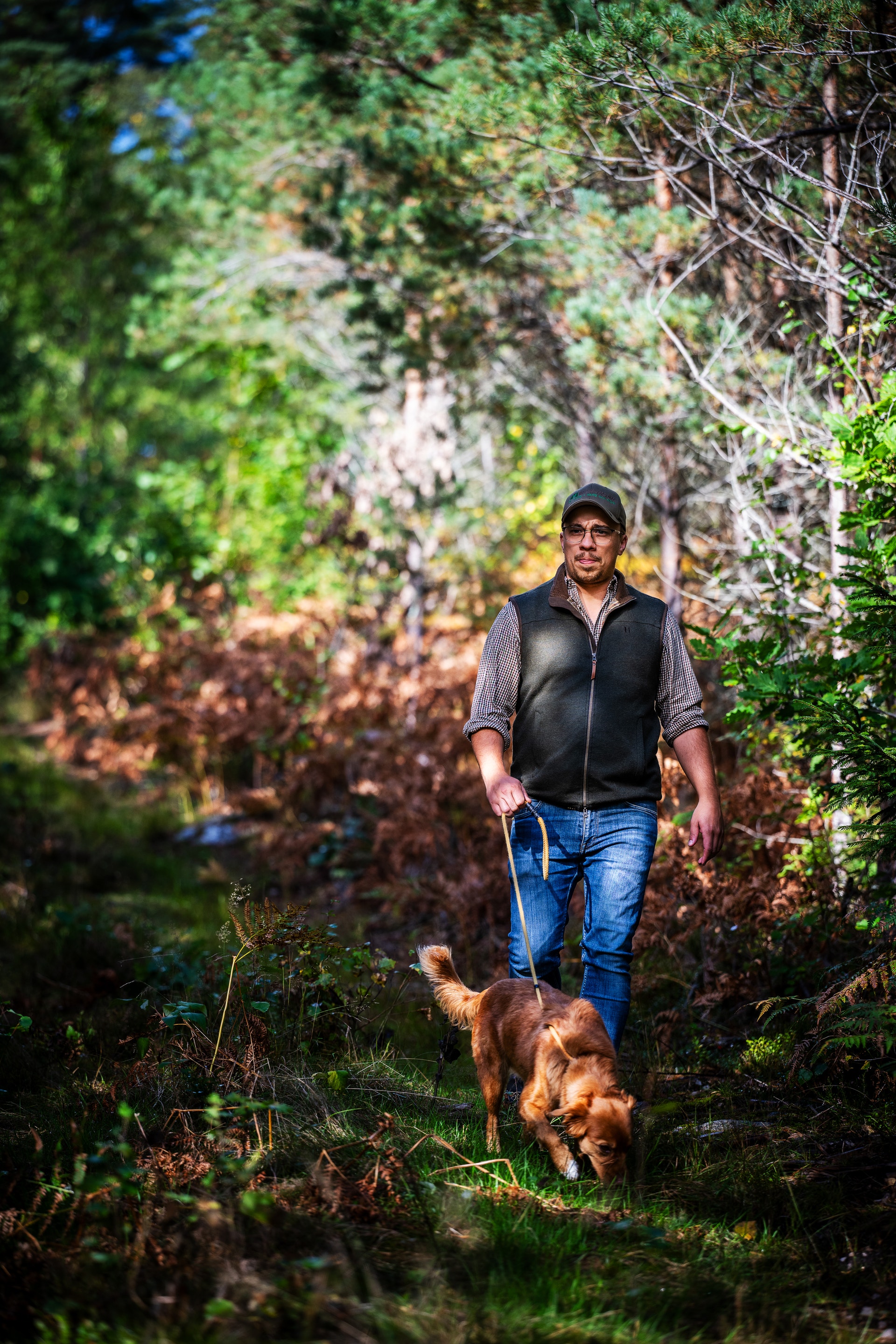 En man går med sin hund i skogen.