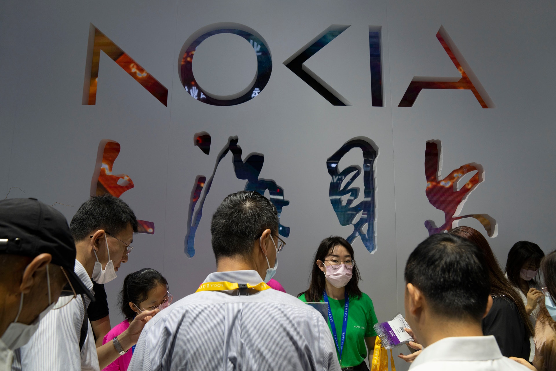 Grupp människor står framför en vägg med stora färgglada bokstäver som bildar ordet Nokia.