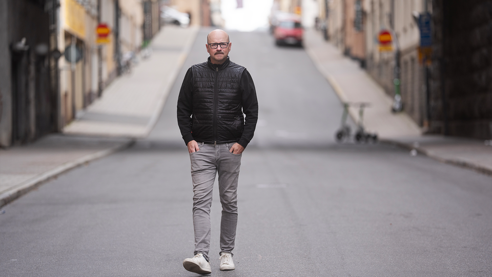 Pål Ahlsén går på gatan, mot fotografen. Han har händerna i fickorna.