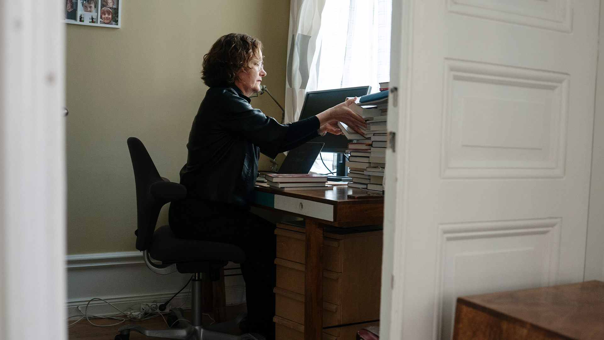 En person sitter vid ett skrivbord och arbetar med dokumenthögar.