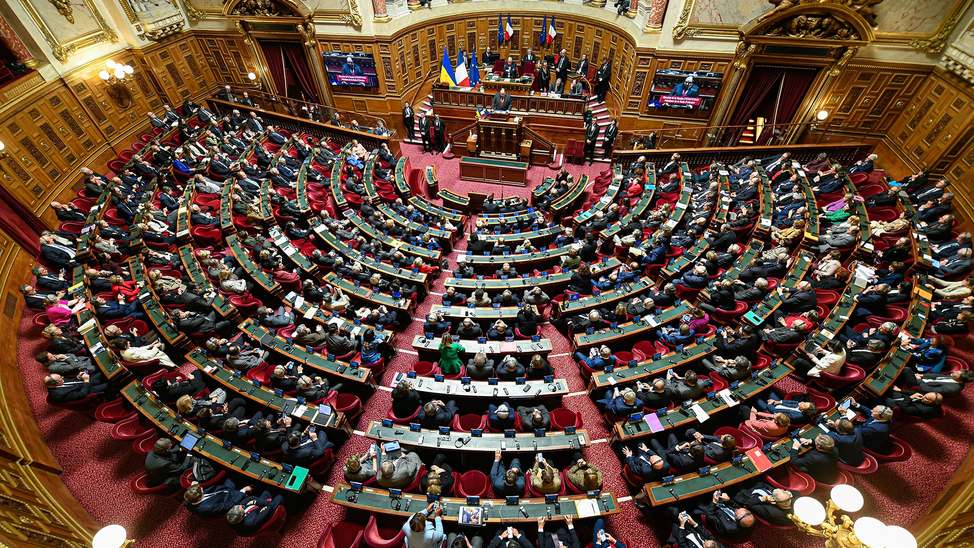 Överblick av en parlamentarisk kammare fylld med många sittande representanter vid sina platser.