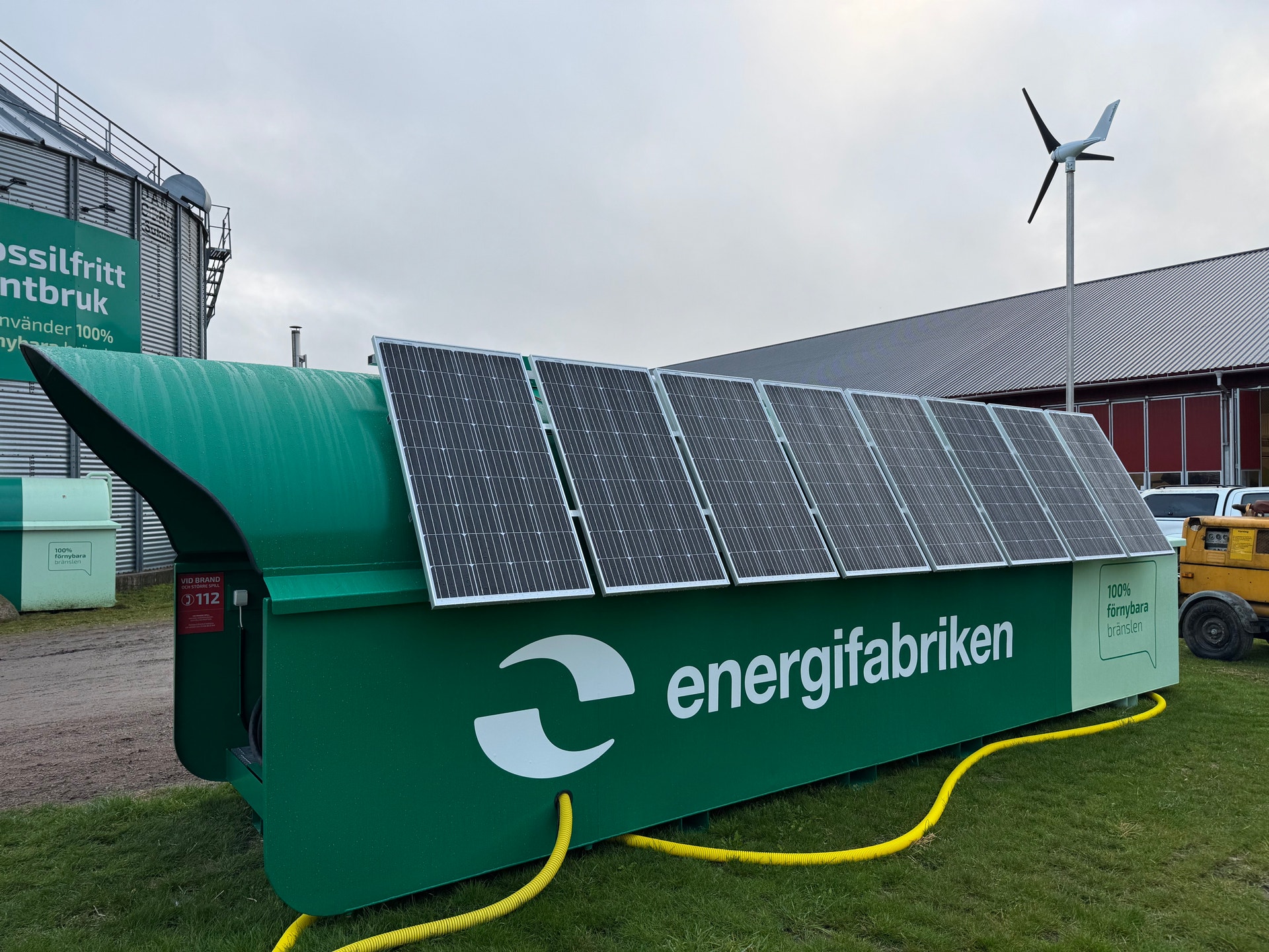 Grön mobil enhet med solpaneler på taket och ett litet vindkraftverk bredvid, märkt Energifabriken.