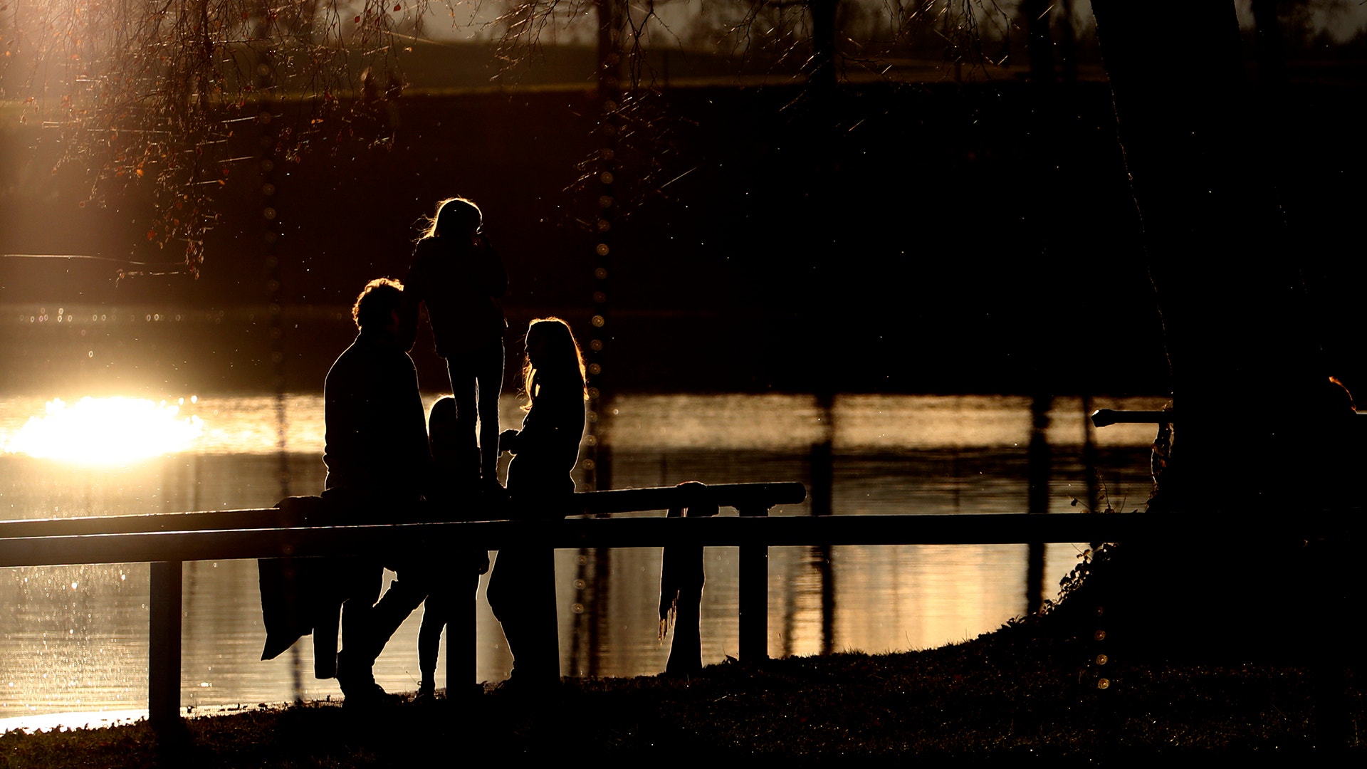 En familj på en brygga vid vattnet i solnedgångslljus
