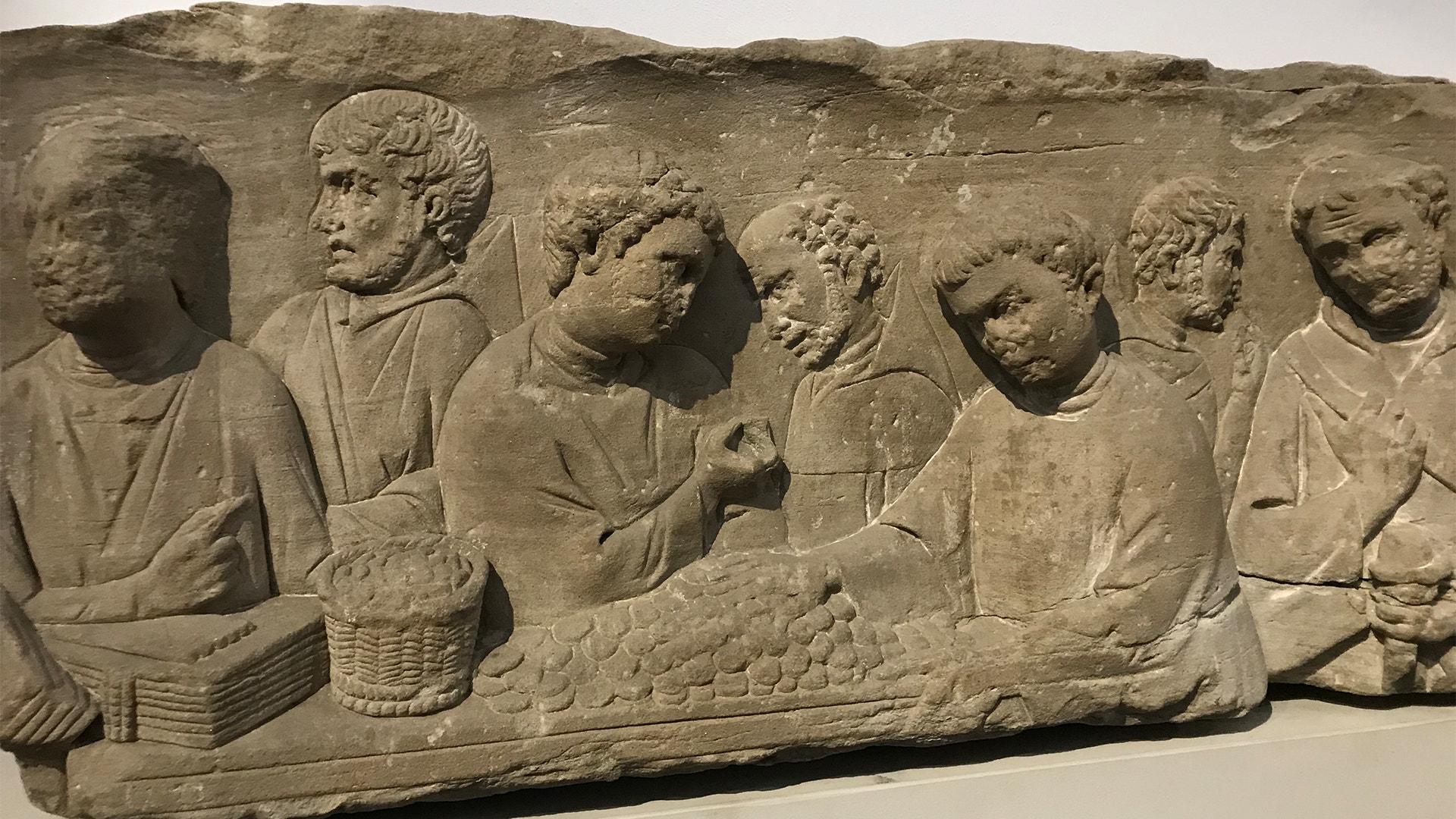 Antik stenrelief med flera människofigurer i relief, möjligen från romersk tid eller tidigare perioder.