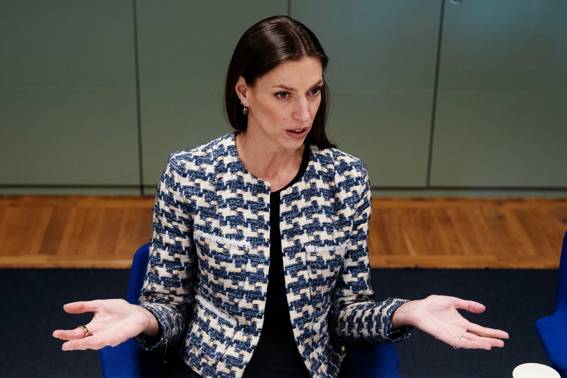 Kvinna i blå och vit mönstrad jacka som gestikulerar under ett föredrag eller presentation