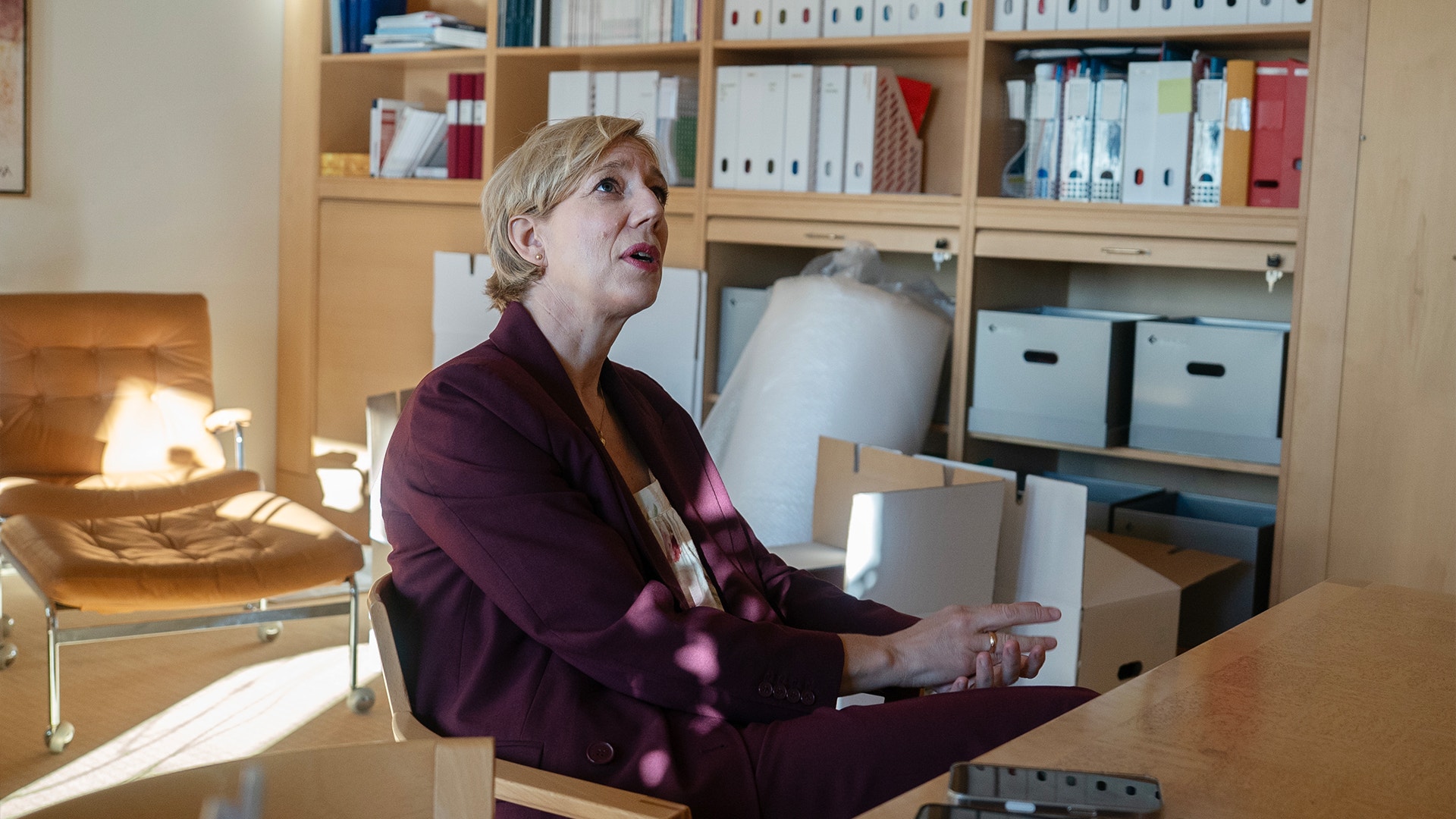 Anna Breman sitter på sitt kontor på Riksbanken. Bakom henne står öppna flyttkartonger.
