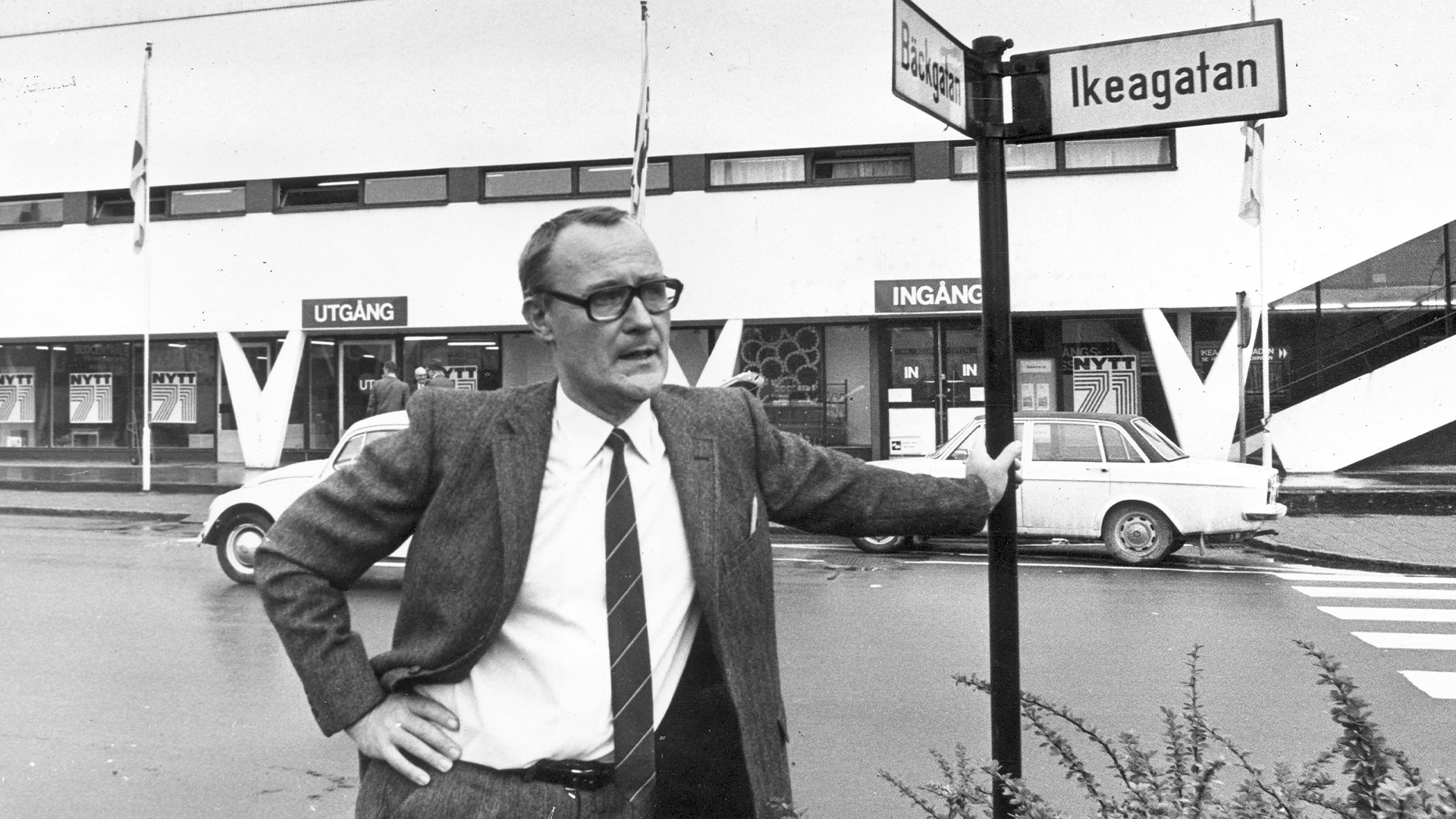 Man i kostym poserar framför IKEA-butik vid en gatuskylt