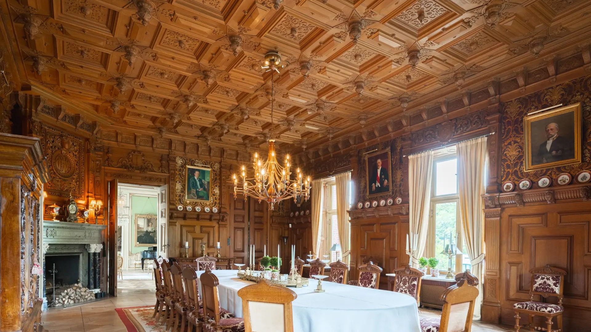 Elegant klassisk matsalsinteriör med träpanelerade väggar, kristallkrona och möblerad matbord.