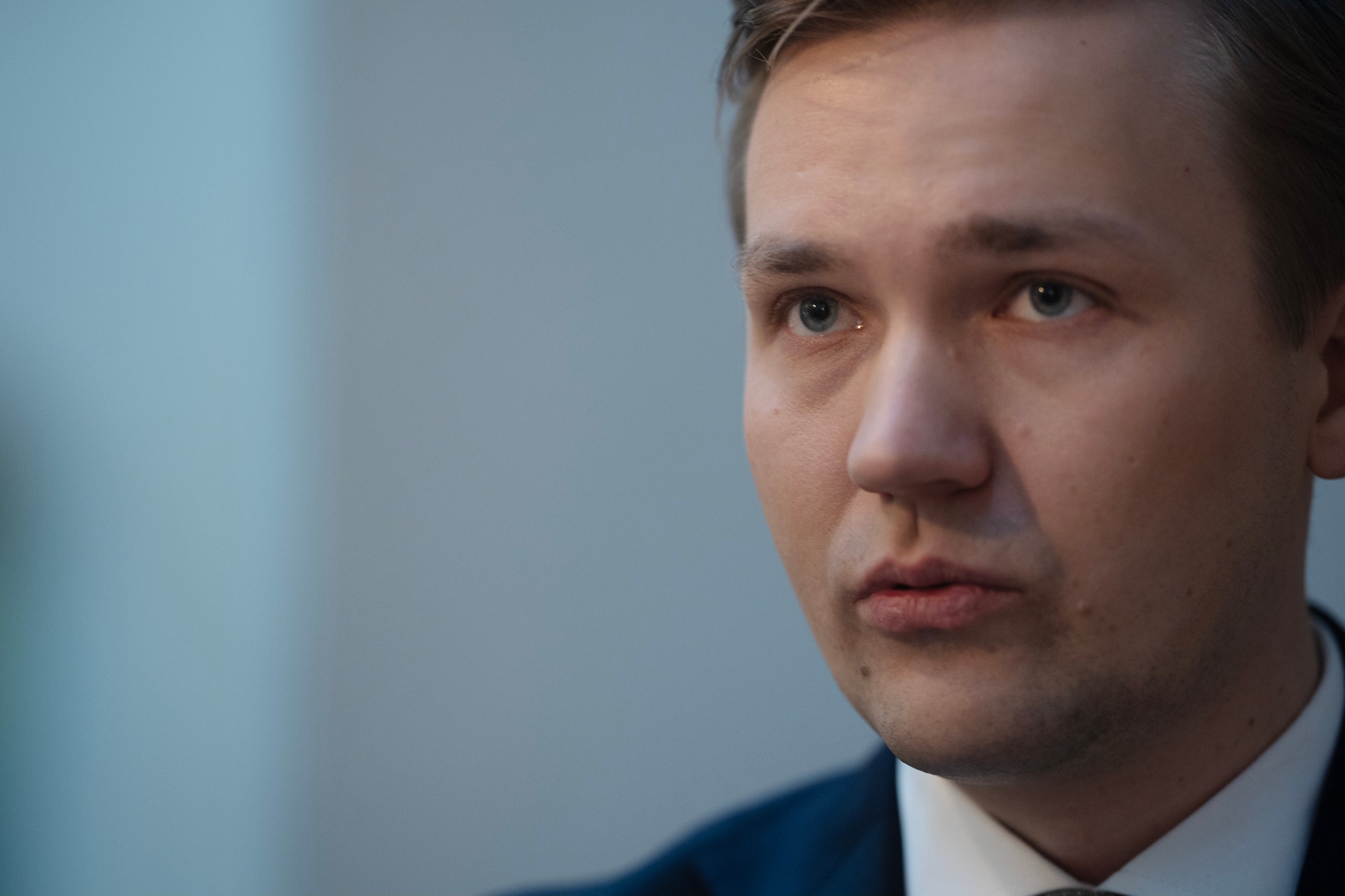 Porträtt av en man i blå kostym mot neutral bakgrund